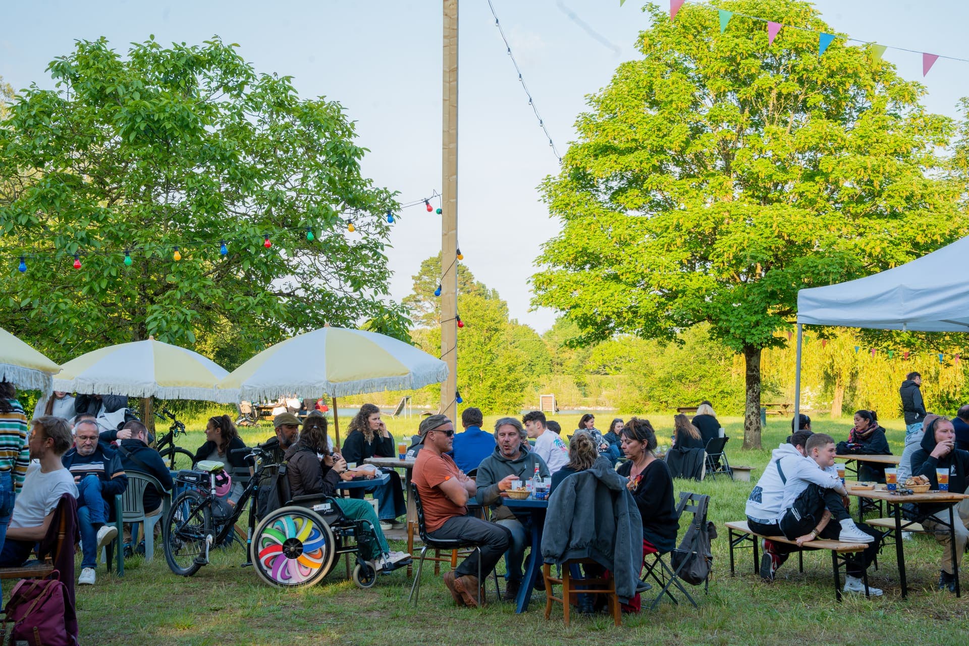 Terrasse au bord de l'étang, guirlandes et public à la guinguette